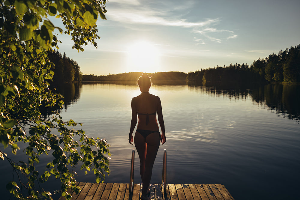A Finnish girl on a peer on a summer evening about to go swimming in a lake