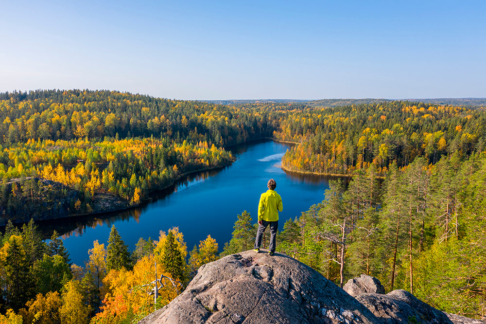 A man standing on a hill in autumn and looking over a lake