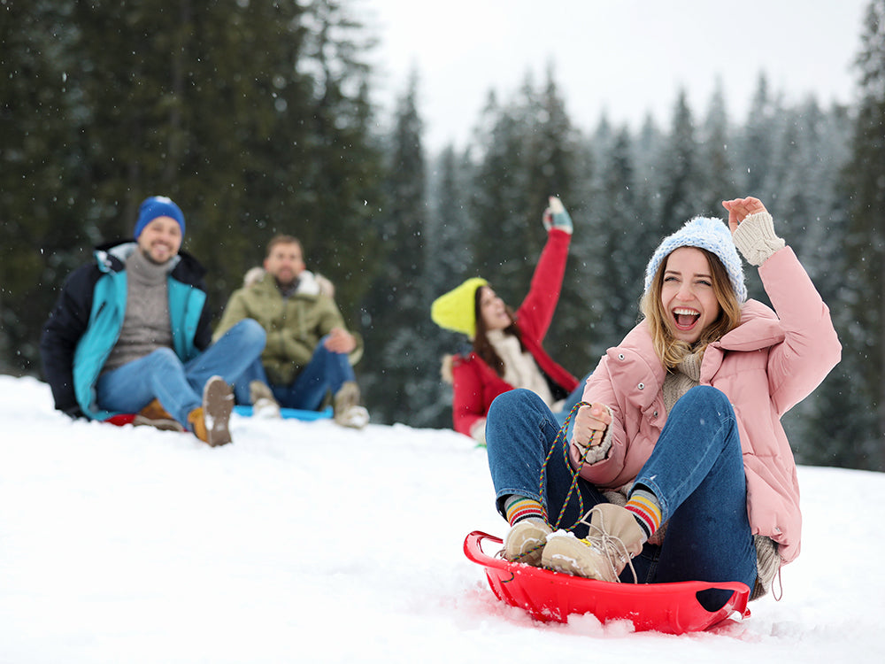 Friends sliding sledges in the snow