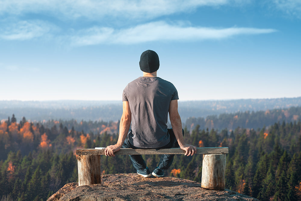 Man sitting on a bench looking at an autumn forest