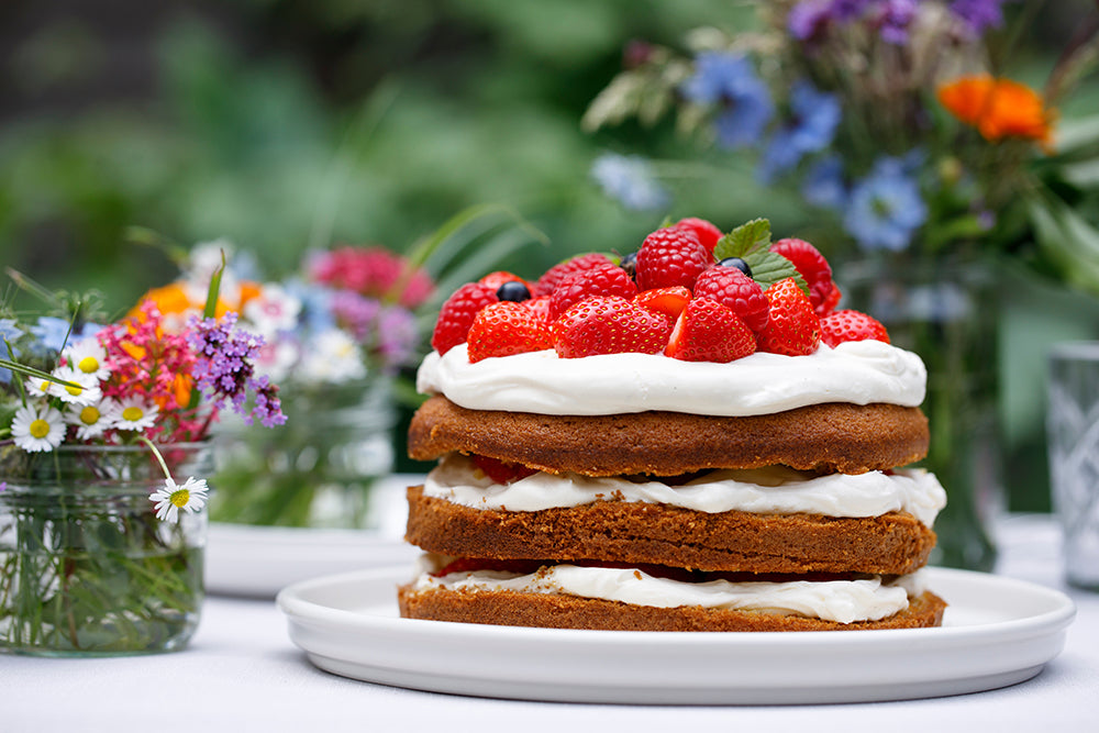 Strawberry cake on a table with flowers in a garden