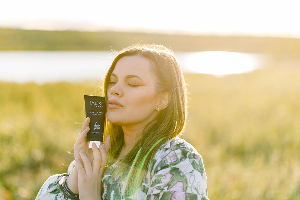 A woman holding a Taiga Cosmetics products on sunny fells in Lapland