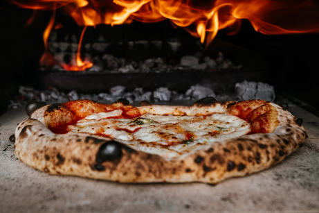 Pizza close_up with burned wood and flame in background