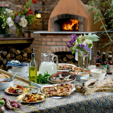 Table with Pizzas and other food with Belforno Pizza oven in background_outdoors