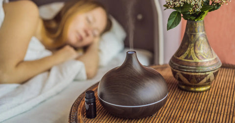 A sleeping woman with a humidifier emitting steam nearby, set in a bedroom environment, indicating the use of aromatherapy and humidity control for improved sleep quality.