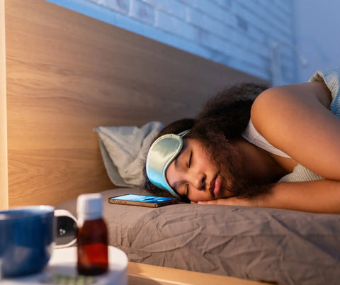 A young woman in sleepwear with an eye mask on, peacefully sleeping in bed, with a bottle of melatonin and a clock on the bedside table.