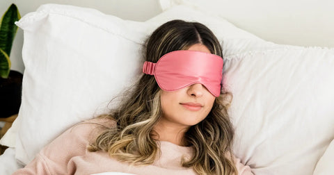 A woman lying in bed wearing a pink sleep mask, comfortably asleep in a well-ventilated room, ideal for maintaining balanced humidity levels during sleep.