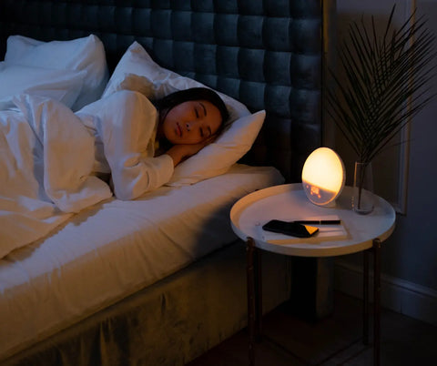 A restful night's sleep in a dark room, with a bedside lamp casting a warm glow, complemented by the ambient sounds of a white noise device.