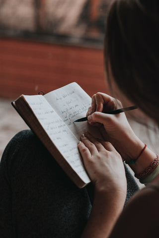 Woman writing on notebook, assessing wellness plan