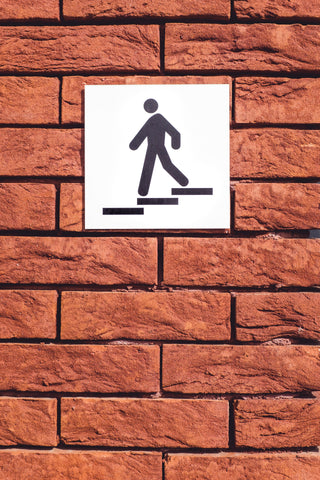 Walking sign posted on brick wall