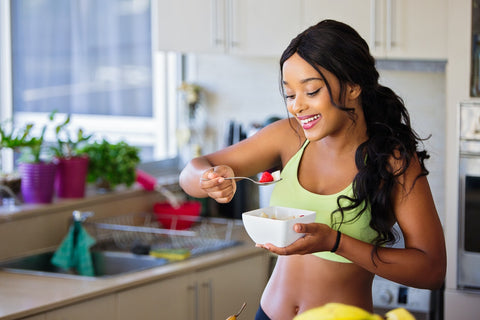 Woman happily eats healthy breakfast after work-out