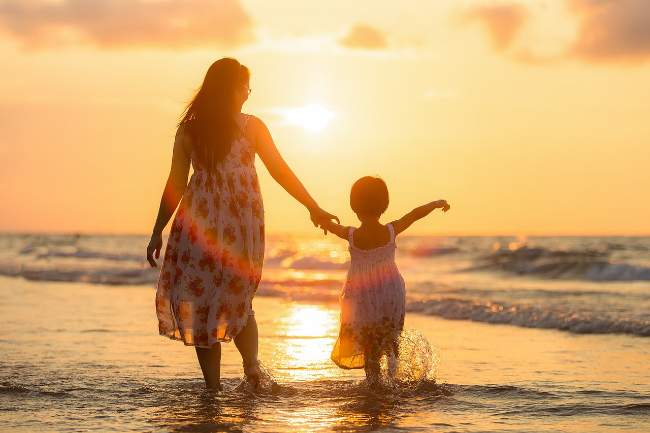 Adult and child holding hands on beach