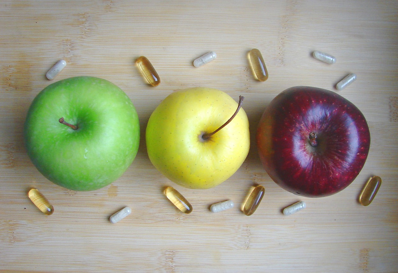 Three apples with supplements around them