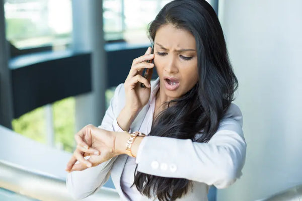 Woman looking at her watch while stressed out for being late.