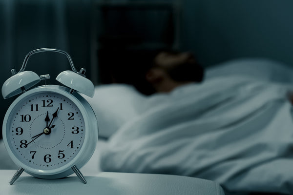 Sleeping person with an alarm clock on their night stand.