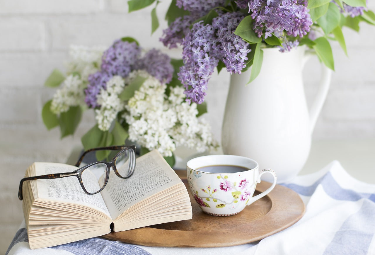 Glasses sitting on an open book with coffee and flowers