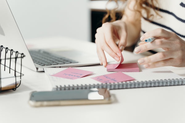 A person writing in a gratitude journal with sticky notes.
