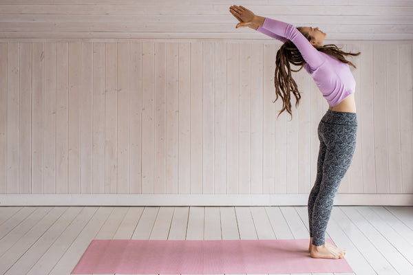 Woman in a yoga studio performing a deep stretch pose.