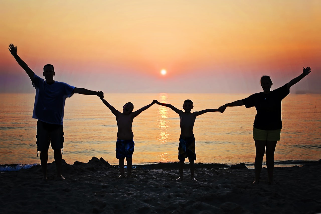 Family silhouetted in front of ocean sunset