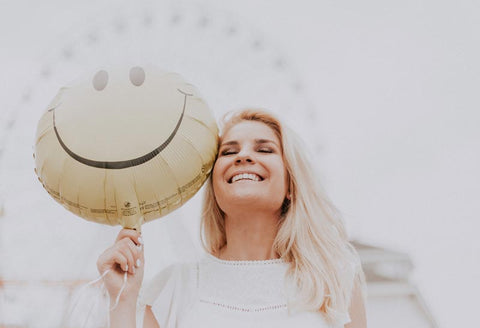 smiling woman holding yellow balloon with happy face