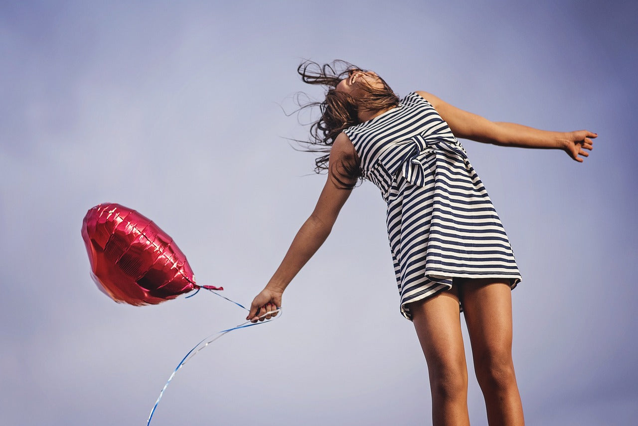 Person standing in wind holding a balloon