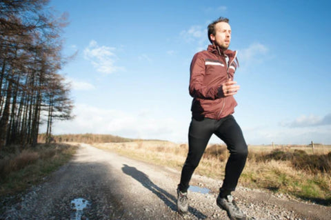 man running on dirt road during a brisk sunny day