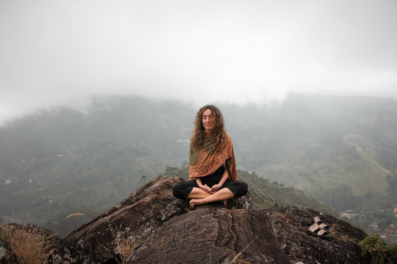 Person sitting serenely on top of mountain