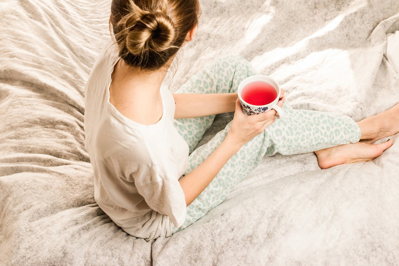 Person sitting on bed with cup of tea