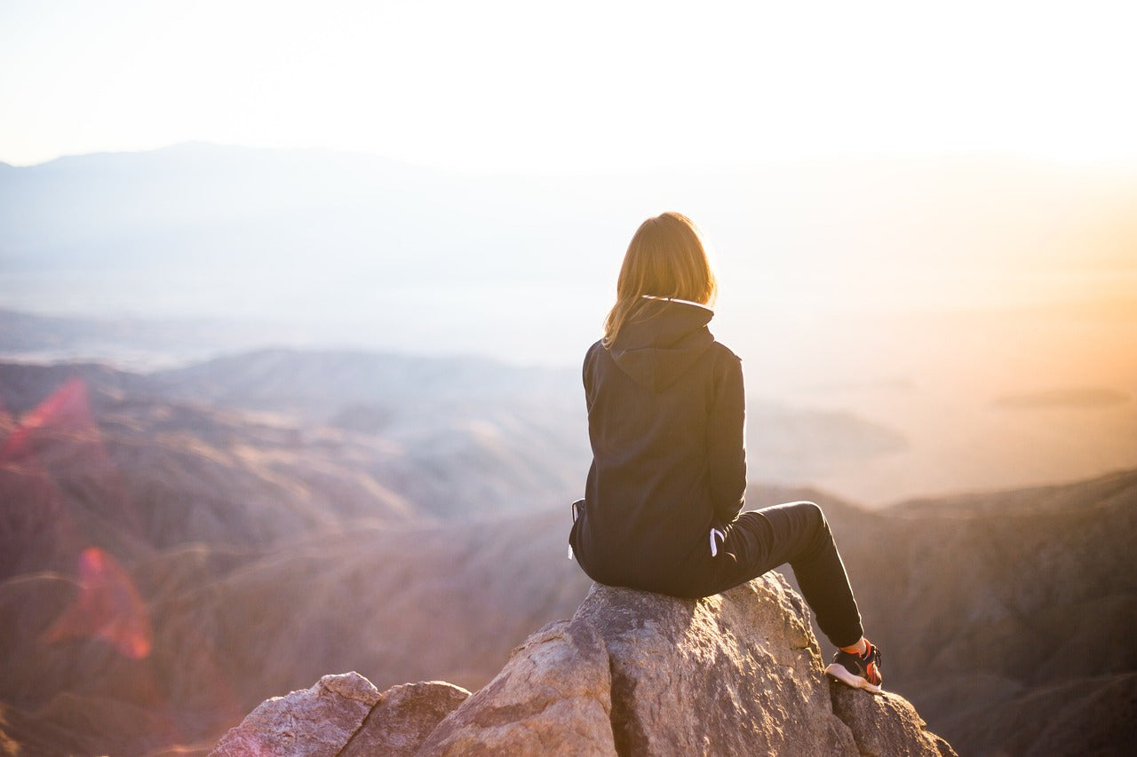 Person sitting on mountain looking at view