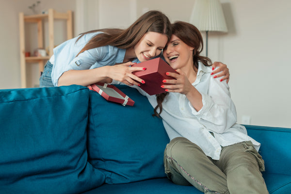 A person experiencing joy while giving a gift to someone, with both individuals smiling warmly.