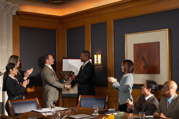 A group of colleagues applauding a team member receiving an award.