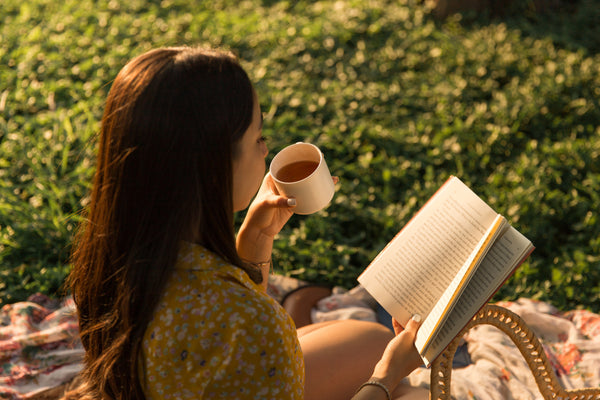 A person reading a book and drinking tea.