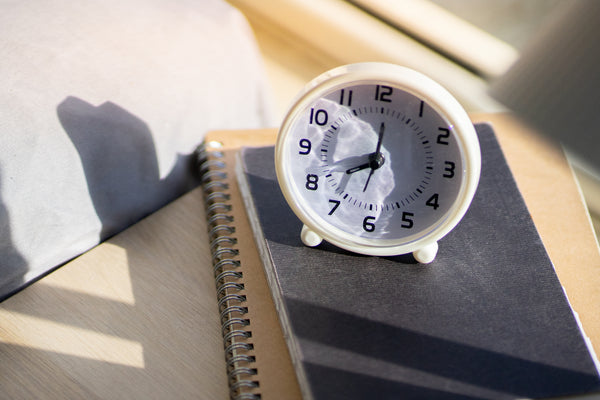 A bedside table with a gratitude journal and a clock showing early morning time.