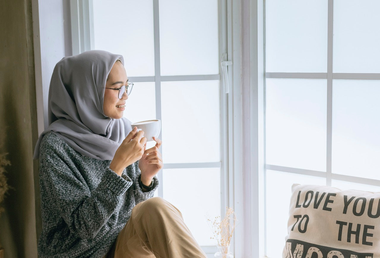 Person looking out window, drinking coffee