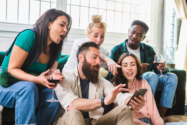 Group of friends pointing at a friend's phone.