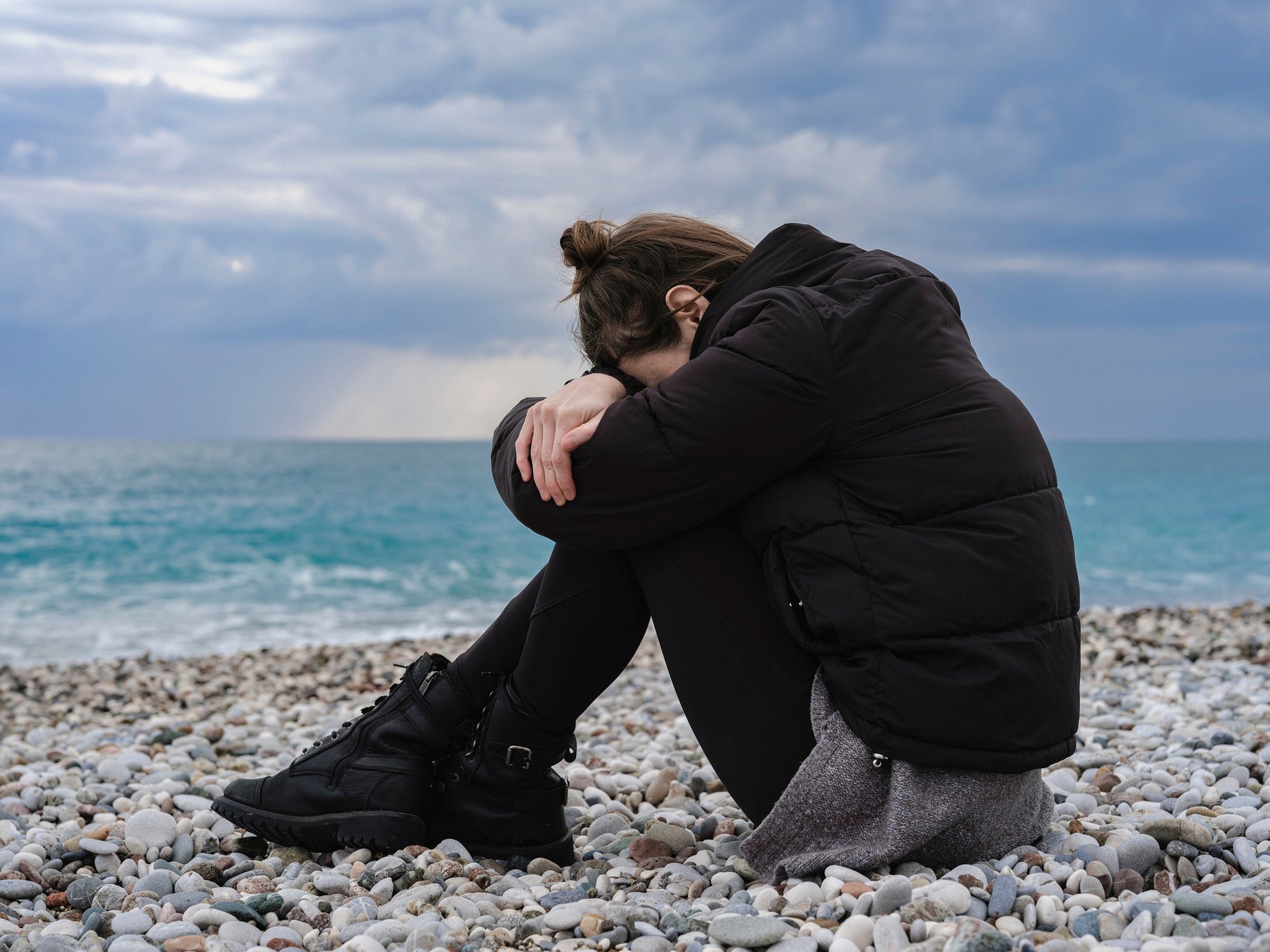 Person sitting on beach hugging their legs