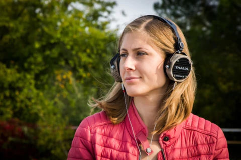 woman outside sunny day listening to music using overear headphones