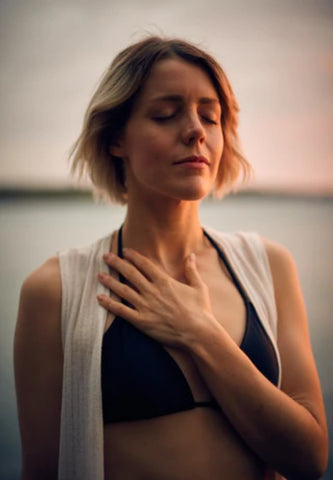 woman in quiet place relaxing and meditating with arm and hand across chest 