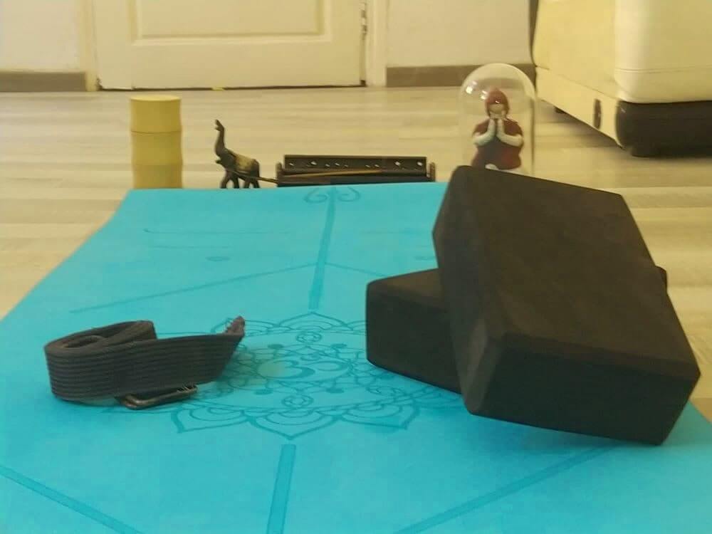 Un tappetino da yoga in schiuma nera, cinturino e mattoni per praticare una sessione di Asthanga