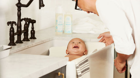 Bebé sonriente en una bañera pequeña