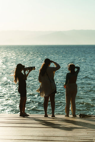 três mulheres de frente para o mar