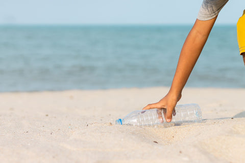 pessoa pegando lixo na areia da praia