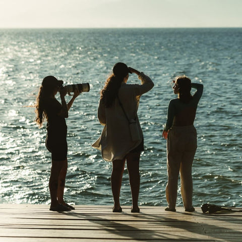 três mulheres de costas olhando para o mar