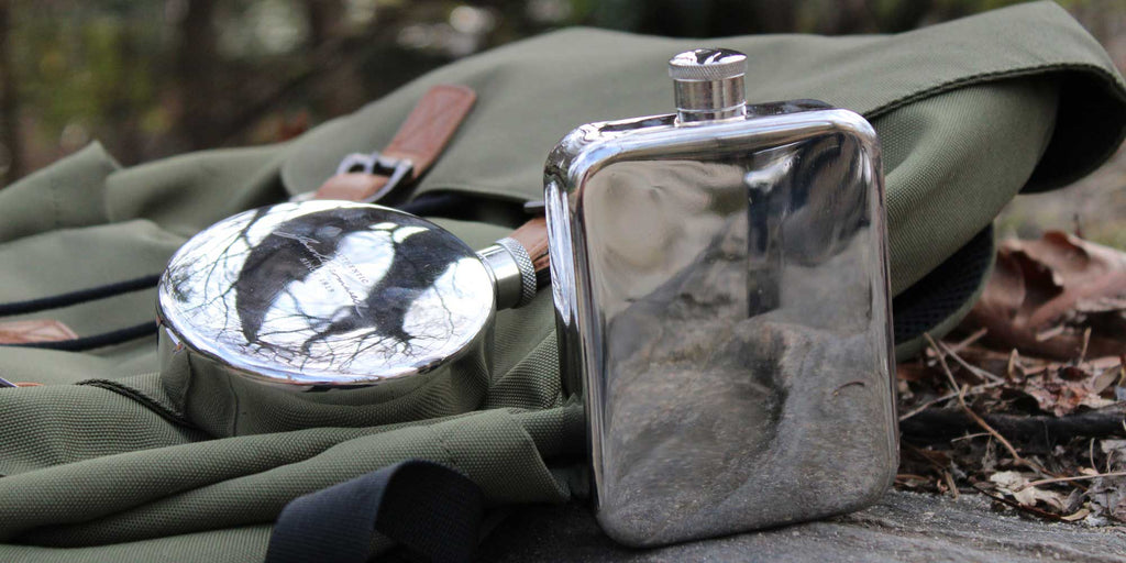 Jacob Bromwell pewter explorer & rover flask on a backpack by a creek