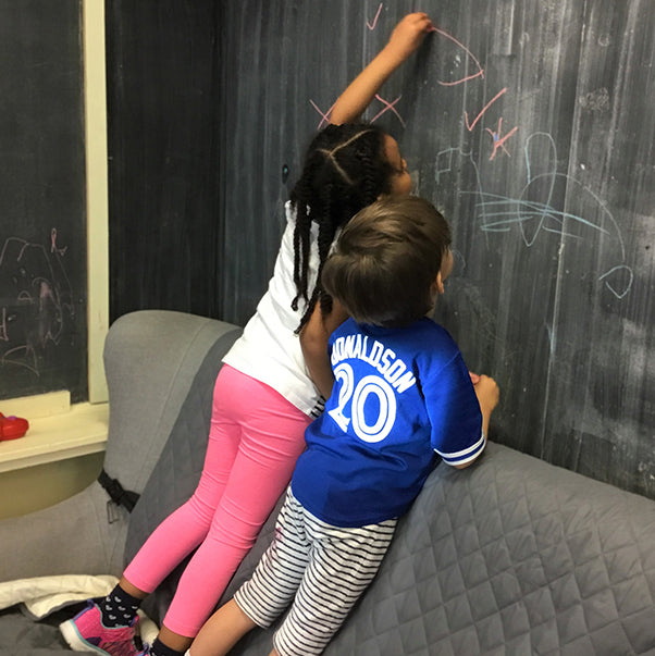 New Haven team member sitting with children around a table while interacting with learning material