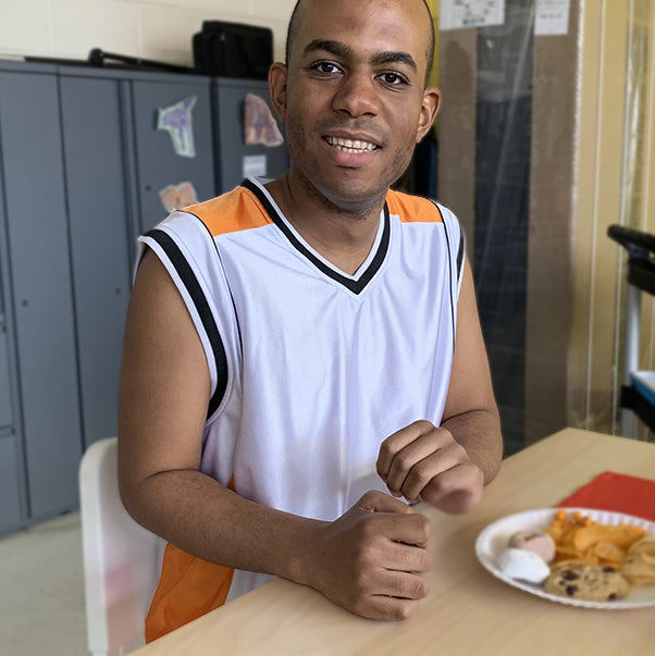 Adult eating at a table while smiling to take a picture