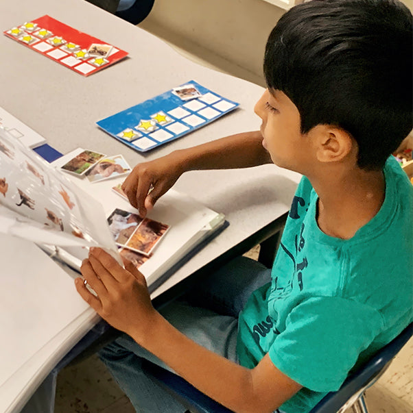 Boy sitting at a table while interacting with learning material