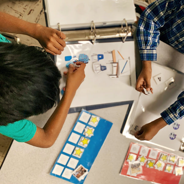 Children sitting at a table while interacting with learning material