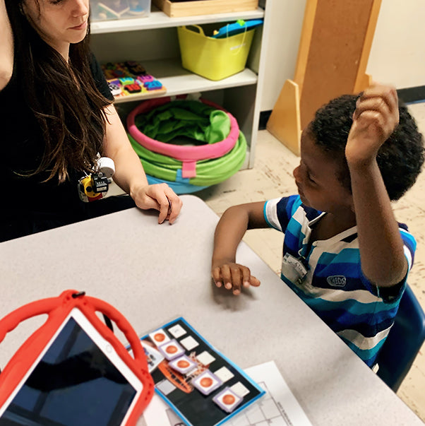 New Haven Team Member sitting with young boy while interacting with learning material