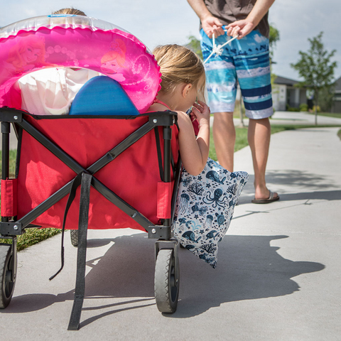 Dad pulling wagon with child and swim gear, to the beach